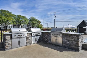 A stone wall with a grill and a white umbrella in the background.